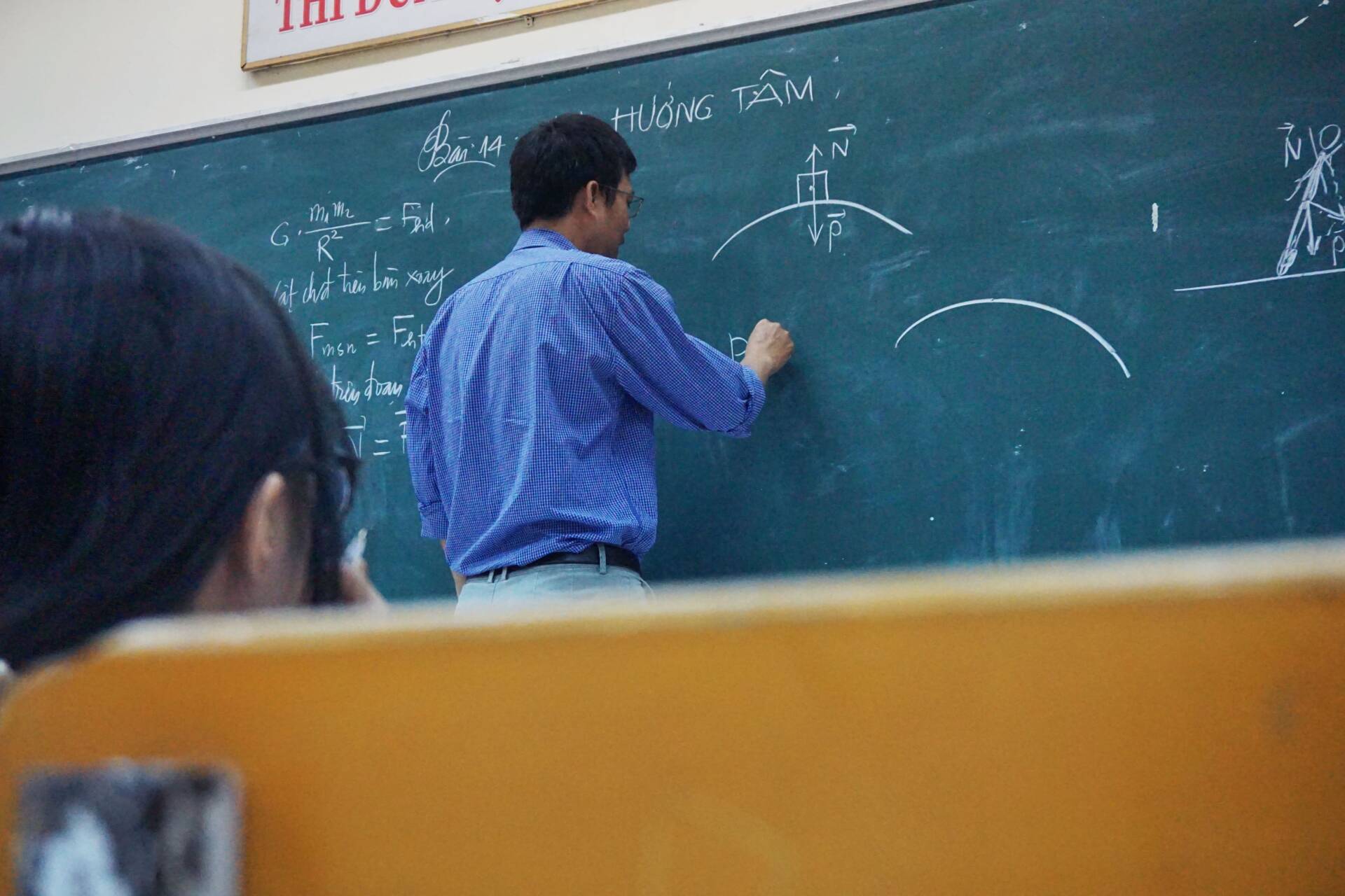 Photograph of a professor writing on a chalkboard.