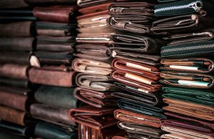 Multiple stacks of leather products, including wallets, books, and pouches