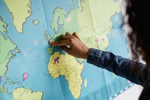 A young girl of color pointing to Europe on a large map of the world