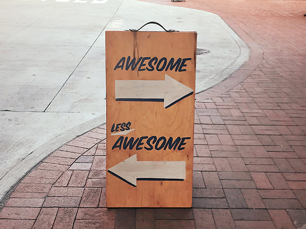 Sandwich board with one arrow pointing towards "Awesome" and a second arrow pointing towards "Less Awesome"