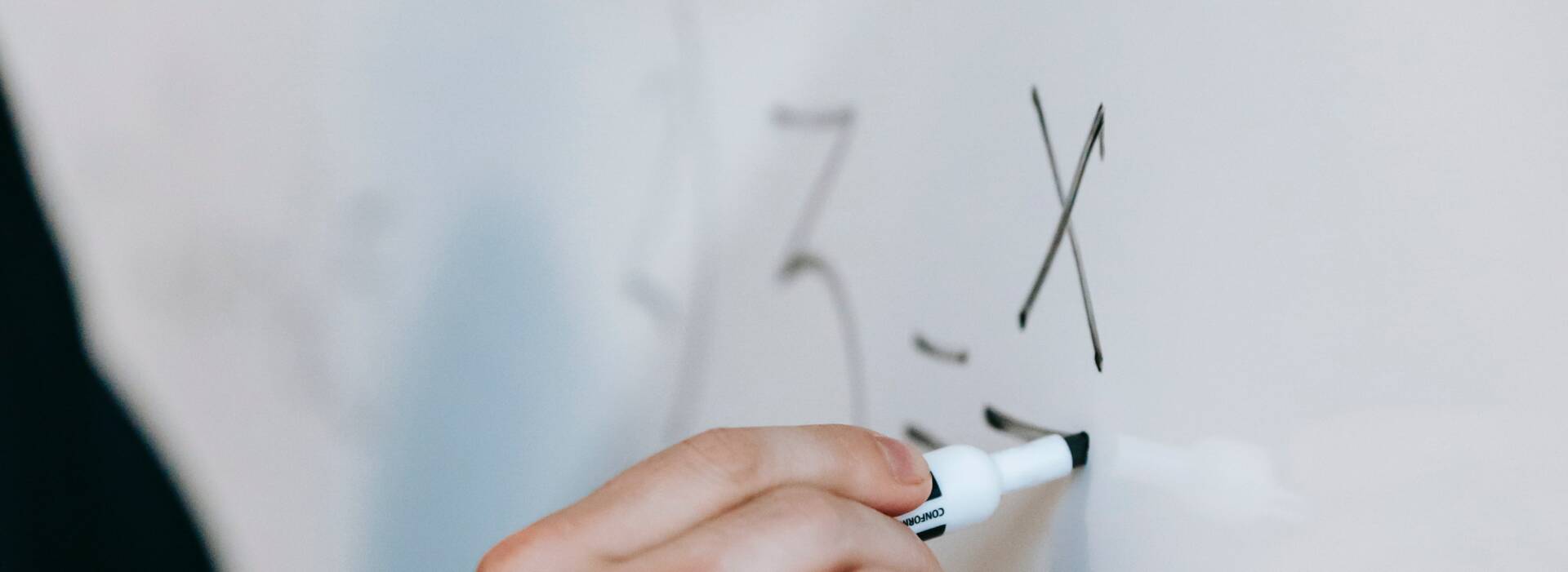 Person writing calculus on a whiteboard with a black marker